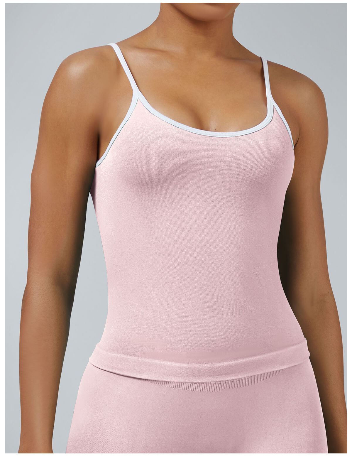 Soft pink seamless workout tank with removable pads featuring white binding detail, feminine athletic wear for gym and fitness